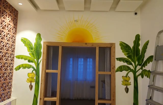 Sunrise Window: A golden sun rising around a window frame, with banana trees painted on either side.
